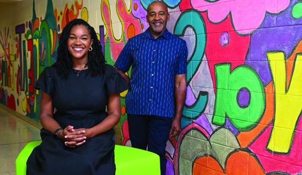 a man and woman stand in front of colorful wall 